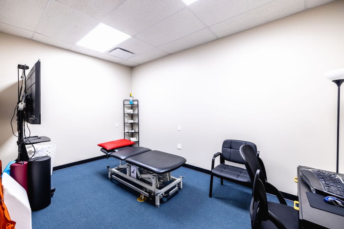 Treatment room with adjustable therapy table, seating, and wall-mounted display