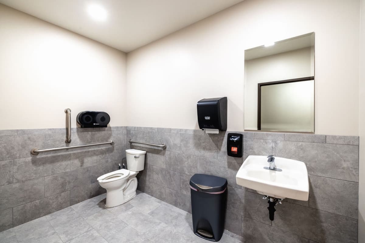 ADA-compliant restroom with grab bars and tile wainscot