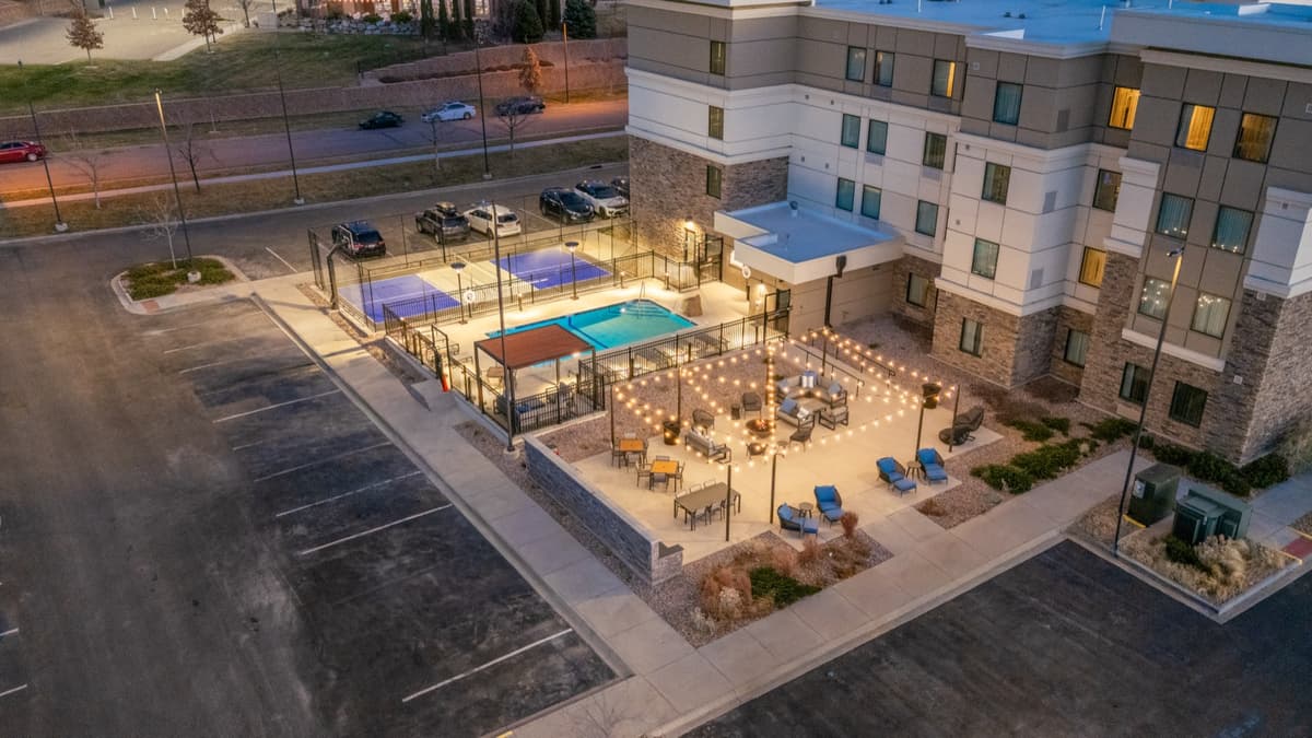 Completed pool, sport court, and patio amenity deck at dusk - Staybridge Suites Littleton