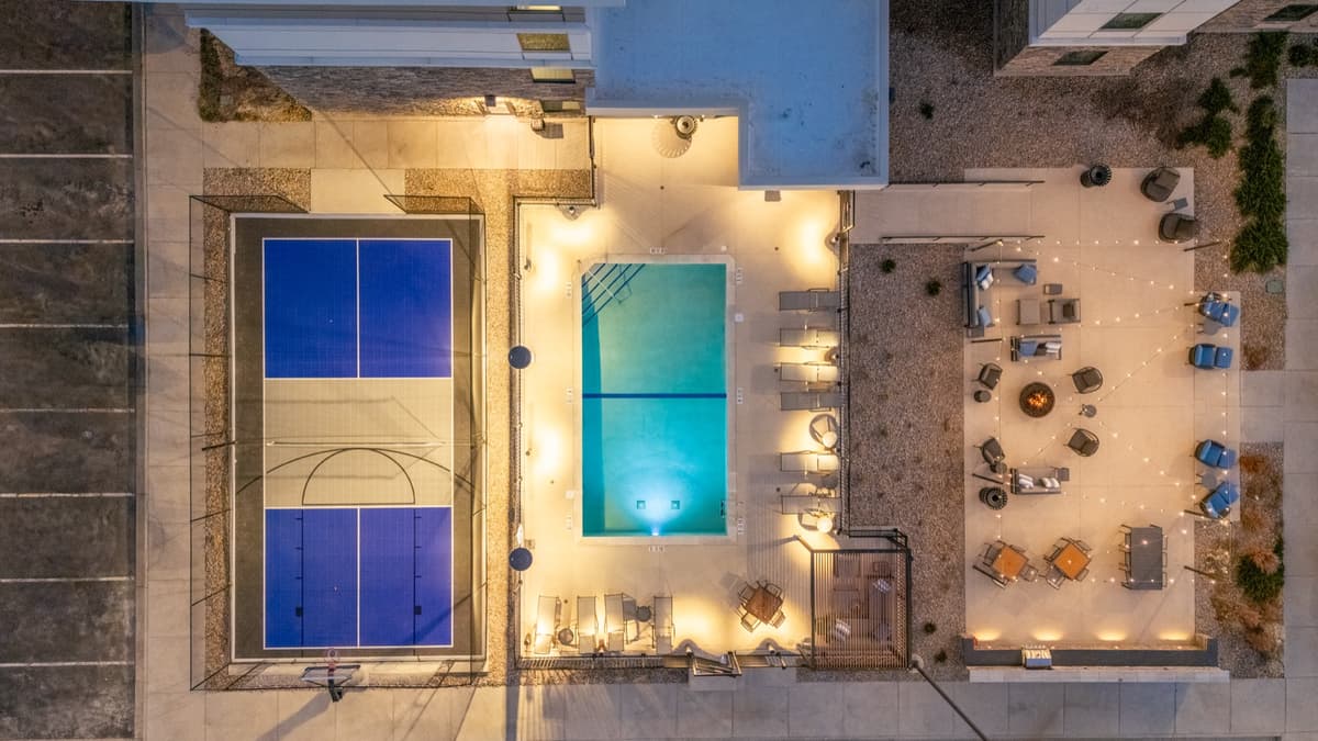 Top-down aerial of the finished pool and amenity deck lit at night