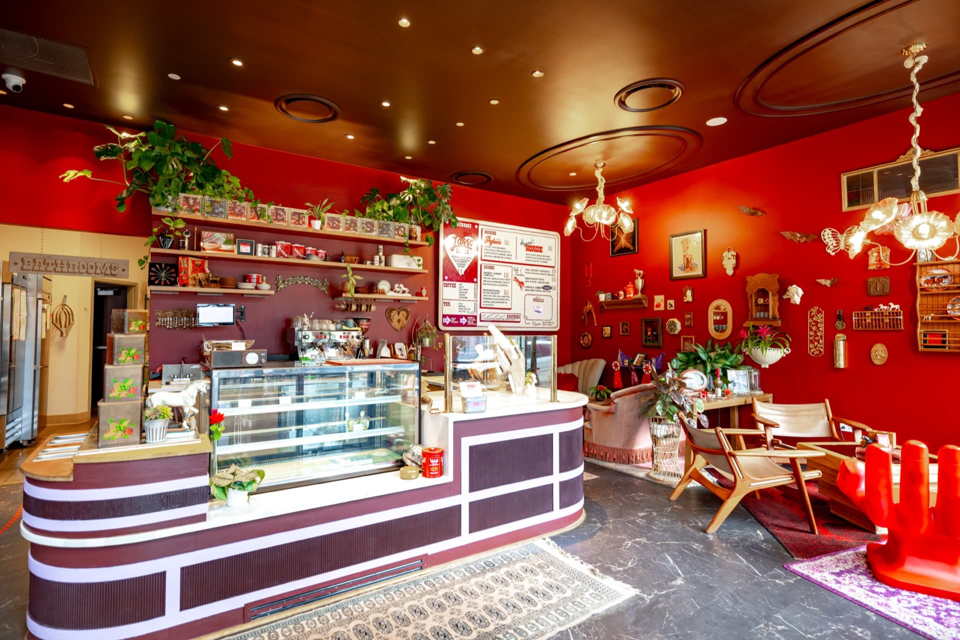 Completed bakery and coffee counter at Velvet Lasso in Denver, with curved striped counter, pastry case, and gallery wall